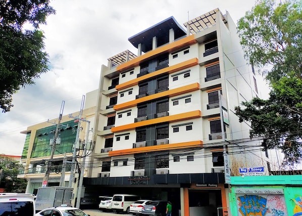 Un edificio de varios pisos con una planta baja comercial, que incluye una tienda 'Big Scoop' y un letrero que indica 'Basement Parking'.