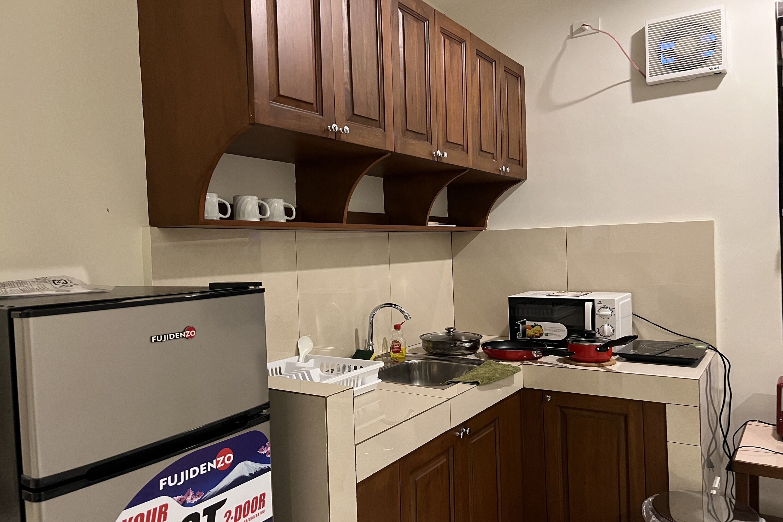 A kitchen with a refrigerator, microwave, sink, and wooden cabinets.