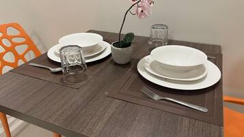 A dining table set with white plates, a clear glass, a small potted plant, and a fork.