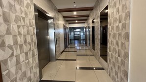 A hallway with geometric patterned walls, a tiled floor, and a ceiling with wooden beams and recessed lighting. - Verjandel Residences (Quezon City)