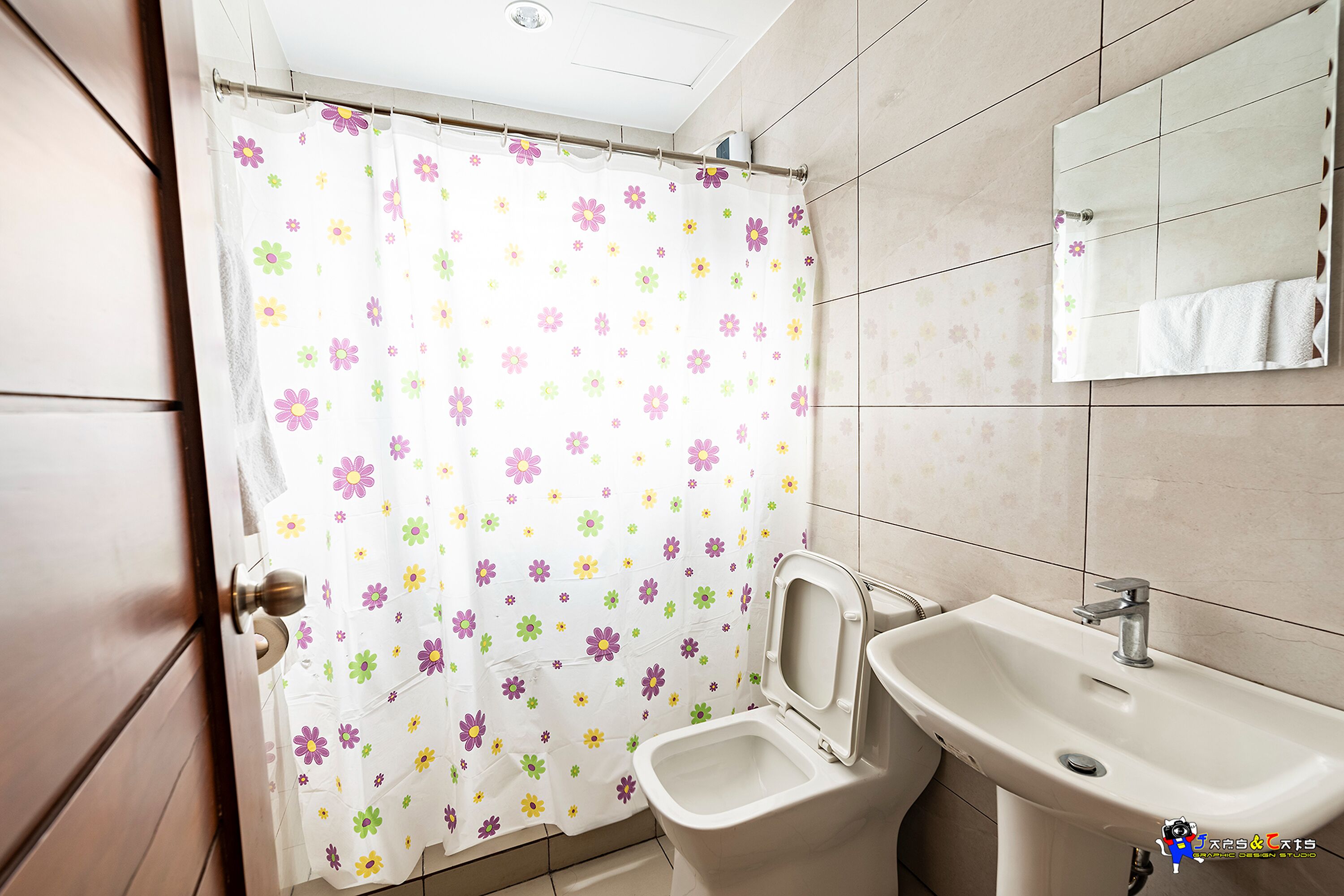Un baño con inodoro, lavamanos y cortina de ducha con estampado floral.