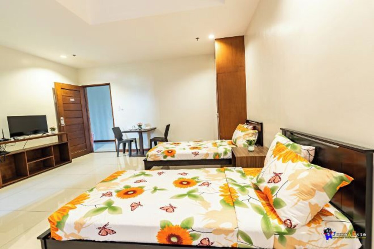A hotel room with two beds, a TV, a desk, and a chair.