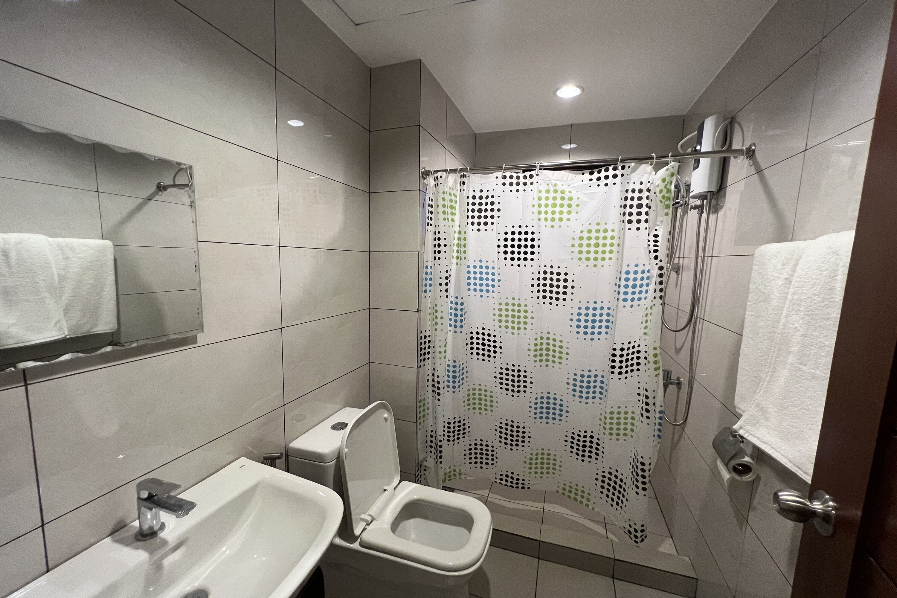 A modern bathroom with a toilet, sink, and shower curtain.