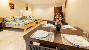 A hotel room with a bed, a dining table set for two, and a small desk with a chair. - Verjandel Residences (Quezon City)