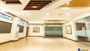 A spacious hallway with a modern design, featuring a staircase, glass doors, and framed artwork on the walls. - Verjandel Residences (Quezon City)