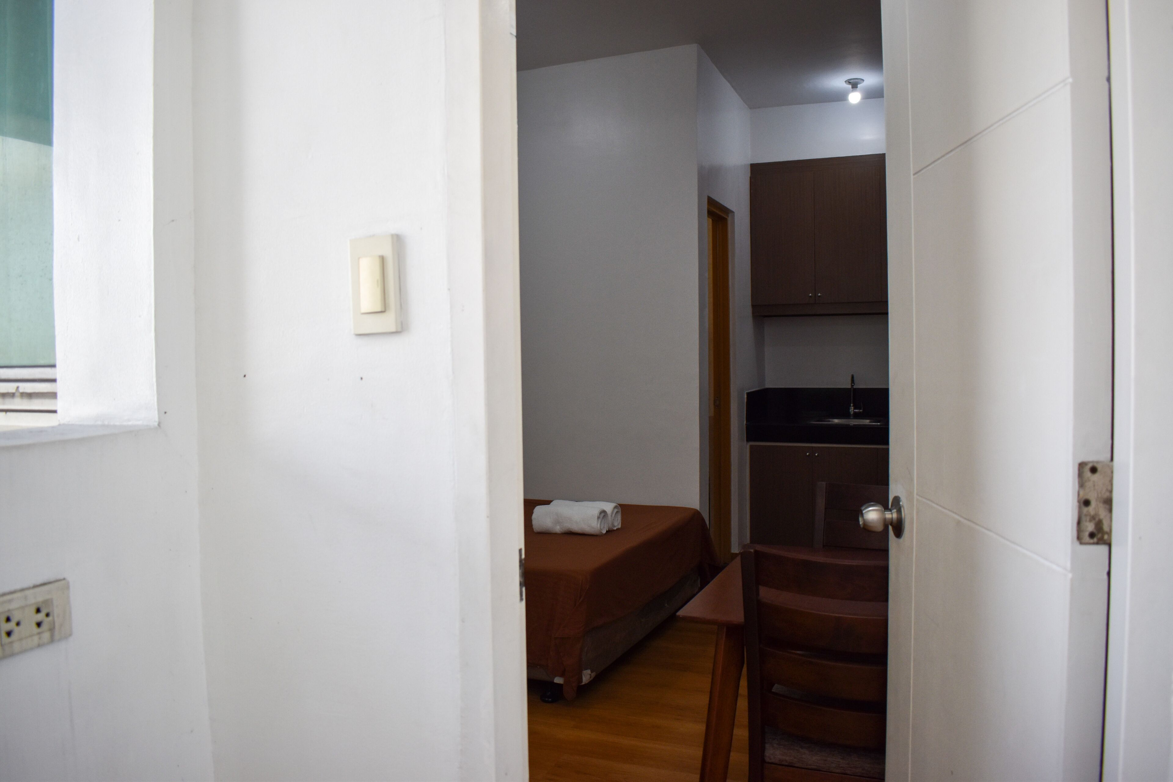 Una habitación con cama, una mesita y un espacio tipo kitchenette.