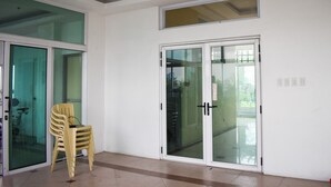 A room with a glass door leading to a balcony, a chair, and a small table. - The Boni Tower By Rspl (Mandaluyong)