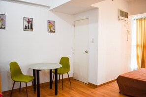 A room with a bed, a table with two chairs, a door, and three wall-mounted pictures. - The Boni Tower By Rspl (Mandaluyong)