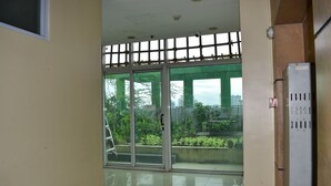 A room with a sliding glass door leading to a balcony with a view of greenery and buildings. - The Boni Tower By Rspl (Mandaluyong)
