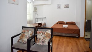 A small, well-lit room with a bed, a chair, and a desk. - The Boni Tower By Rspl (Mandaluyong)