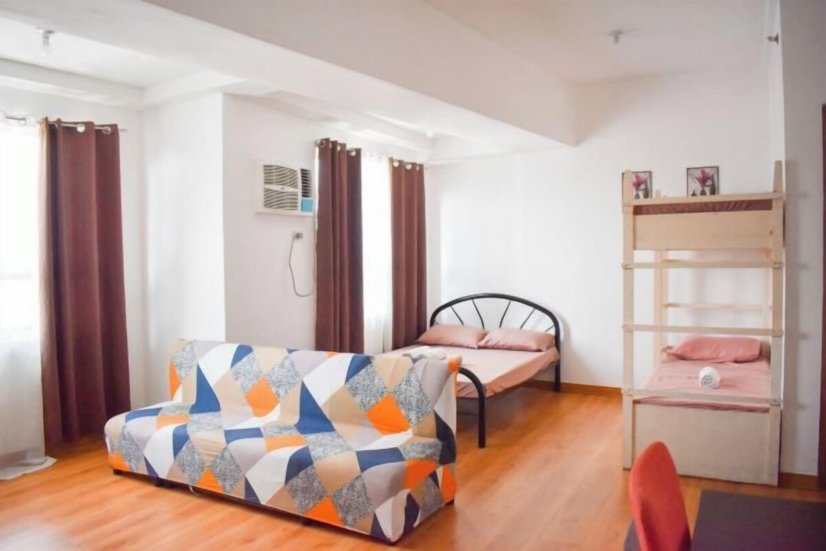 A room with a sofa, a bed, a bunk bed, and a chair.