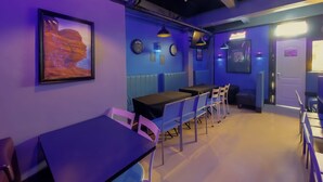 A restaurant with purple lighting, tables, chairs, and a clock on the wall. - 1812 Vc Lodge (Manila)