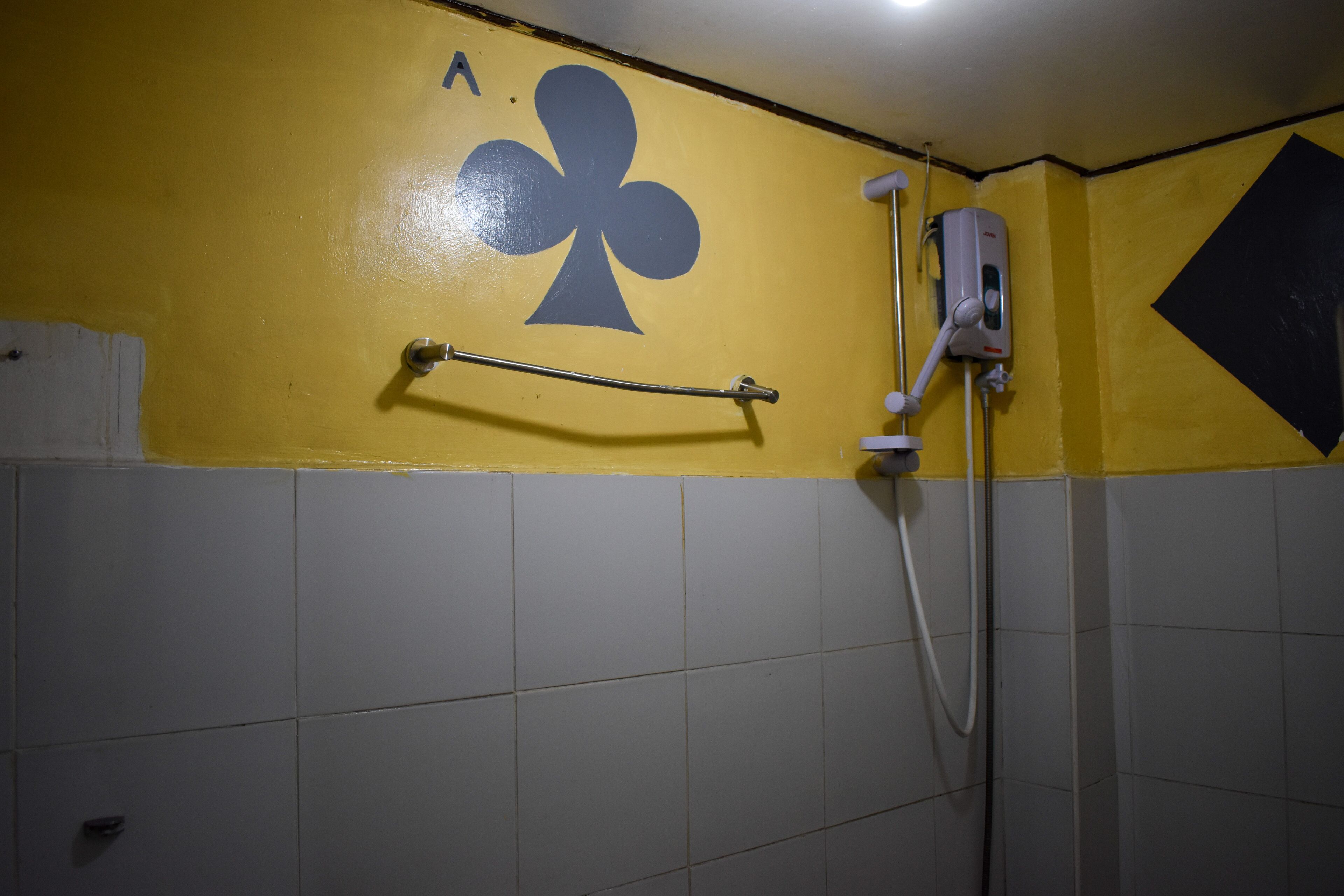 A bathroom with yellow walls, a hand dryer, and a towel rack.