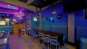 A restaurant with booths and tables, a bar area, and blue lighting. - 1812 Vc Lodge (Manila)
