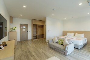 Habitación de hotel con cama, mesita de noche, escritorio con silla, armario y baño.