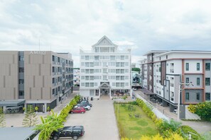 Un hotel moderno con un ampio atrio centrale, diversi piani e un'area parcheggio con automobili.