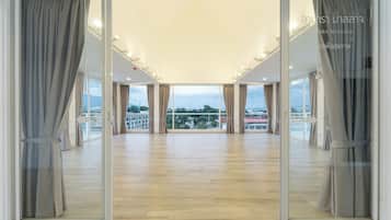 Una habitación amplia con ventanas grandes, suelo de madera y cortinas.