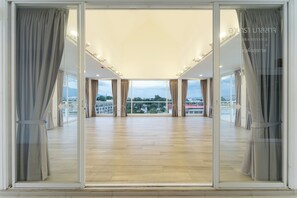 A spacious room with large windows, wooden flooring, and curtains. - Arsh Boutique Hotel (Chiang Mai)