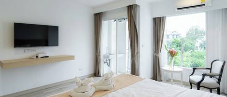 A hotel room with a bed, a TV, a sink, a shower, a chair, and a view of the outdoors.