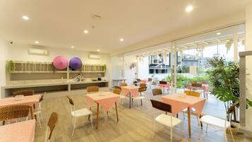 Un restaurante con mesas en el interior, una zona de cocina y vistas al exterior.