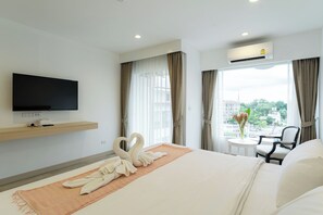 A hotel room with a bed, a flat-screen TV, a small table with a chair, and a window with curtains. - Arsh Boutique Hotel (Chiang Mai)