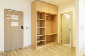 Una habitación con un armario de madera, una puerta con cerradura y un perchero con ganchos.