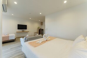 Una habitación de hotel con cama, televisor, minibar y zona de estar.