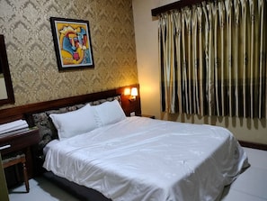 A hotel room with a bed, a nightstand, a lamp, a painting on the wall, and curtains. - Tam Tin Hotel (Ho Chi Minh City)