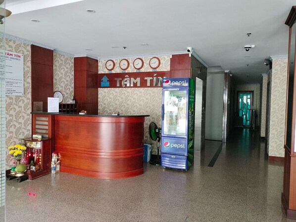 A reception area with a wooden reception desk, a Pepsi refrigerator, and a clock on the wall. - Tam Tin Hotel (Ho Chi Minh City)