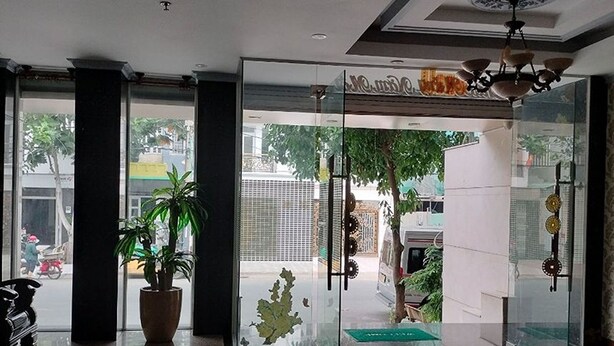 Een moderne lobby met een glazen deur naar buiten, een kamerplant en een kroonluchter.