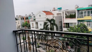 Een balkon met sierlijk metalen hekwerk, uitkijkend op een straat met gebouwen.