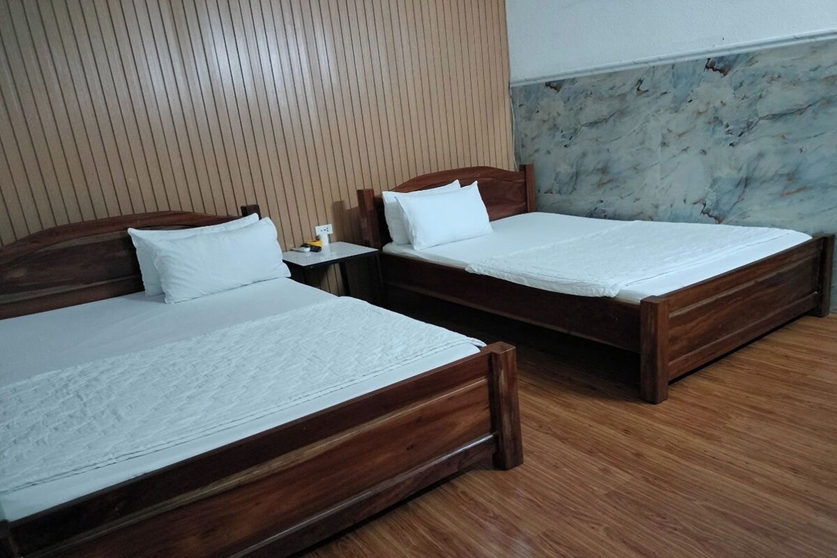 Twee houten bedden met witte lakens in een kamer met houten wandpanelen en een marmeren muur.