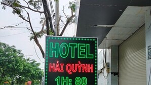 Een hotelschild met groene en rode tekst die kamerprijzen en voorzieningen aangeeft.