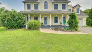 Una casa a due piani con portico anteriore, un piccolo giardino e vialetto.