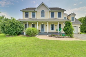 Una casa a due piani con portico anteriore, un piccolo giardino e vialetto.
