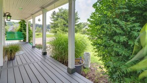 Un portico riparato con un patio in legno, piante verdi e un piccolo giardino.