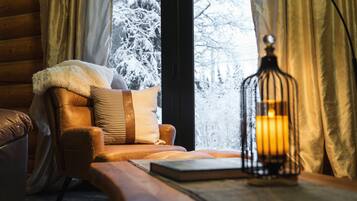 A cozy room with a leather sofa, a wooden table, and a lit candle in a glass lantern.