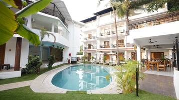 Un hotel con piscina, varios balcones y zonas de estar al aire libre.
