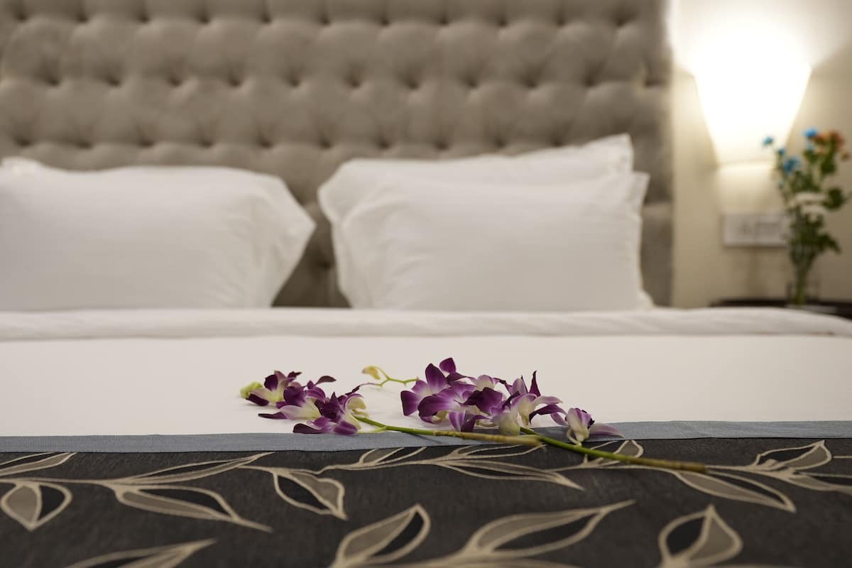 A neatly made bed with white linens and a decorative pillow at the head.