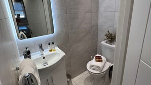 Un baño moderno con lavamanos, espejo y retrete blancos.