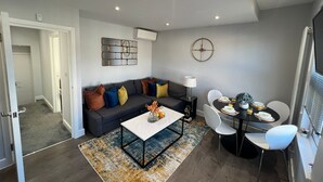 Una sala de estar moderna con un sofá gris, una mesa de centro y un comedor con mesa y sillas.