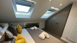 Un dormitorio moderno con una cama grande, tragaluces, un armario y un radiador.