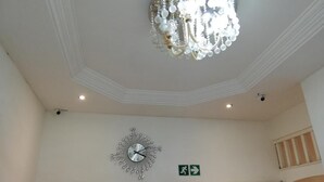 A room with a chandelier, a wall clock, and an emergency exit sign. - Defountain Guest house (Johannesburg)