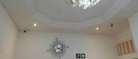 Una habitación con candelabro, un reloj de pared y un letrero de salida de emergencia.
