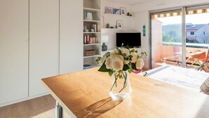 Een moderne keuken met een houten aanrecht, een vaas met bloemen en een eethoek met een tafel en stoelen.