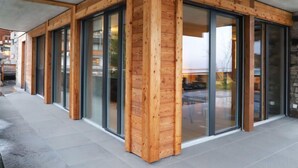 Ein modernes Gebäude mit Holzfassade und großen Glasüren.