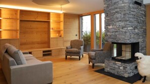 Ein gemütliches Wohnzimmer mit Kamin aus Stein, Holzregalen und bequemen Sitzmöglichkeiten.