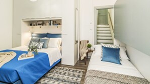 Une chambre moderne avec deux lits, une étagère intégrée, un escalier et un tapis à motifs.