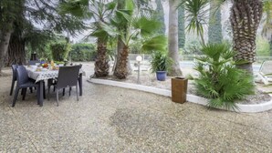 Un área de comedor al aire libre con una mesa dispuesta para dos personas, rodeada de palmeras y un piso de piedra.