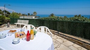 A table set outdoors with breakfast items, overlooking a coastal view.